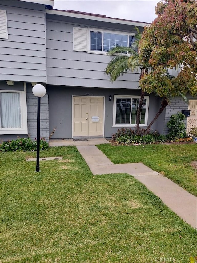 exterior space with brick siding and a front yard