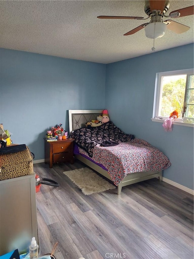bedroom featuring wood finished floors, a textured ceiling, a ceiling fan, and baseboards