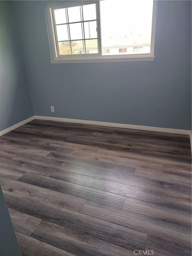 spare room featuring baseboards and dark wood-style floors