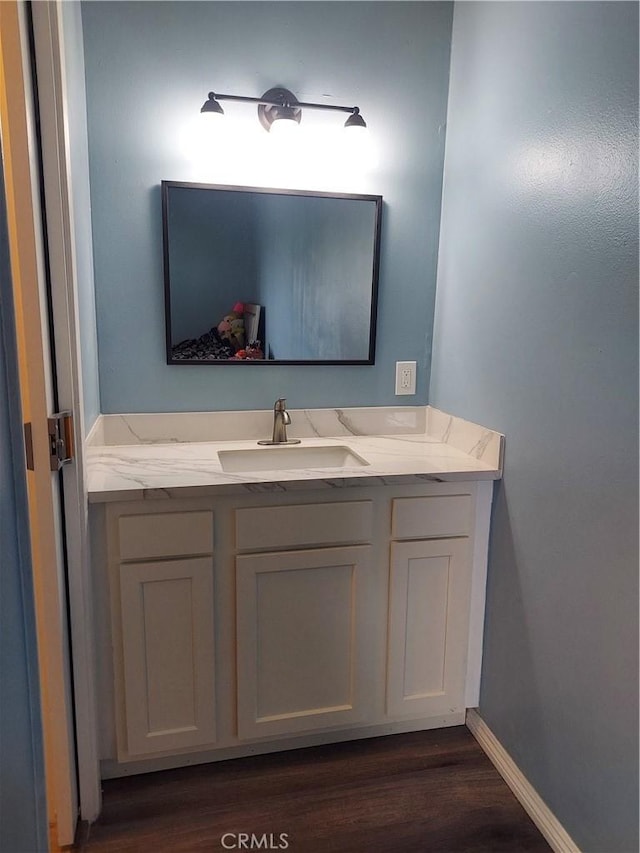 bathroom with baseboards, wood finished floors, and vanity
