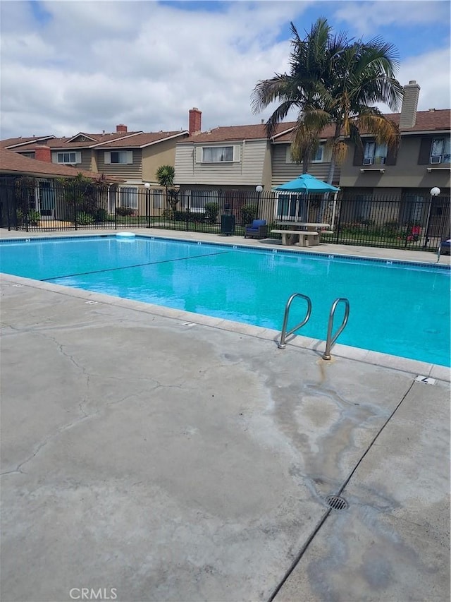 community pool with fence, a residential view, and a patio