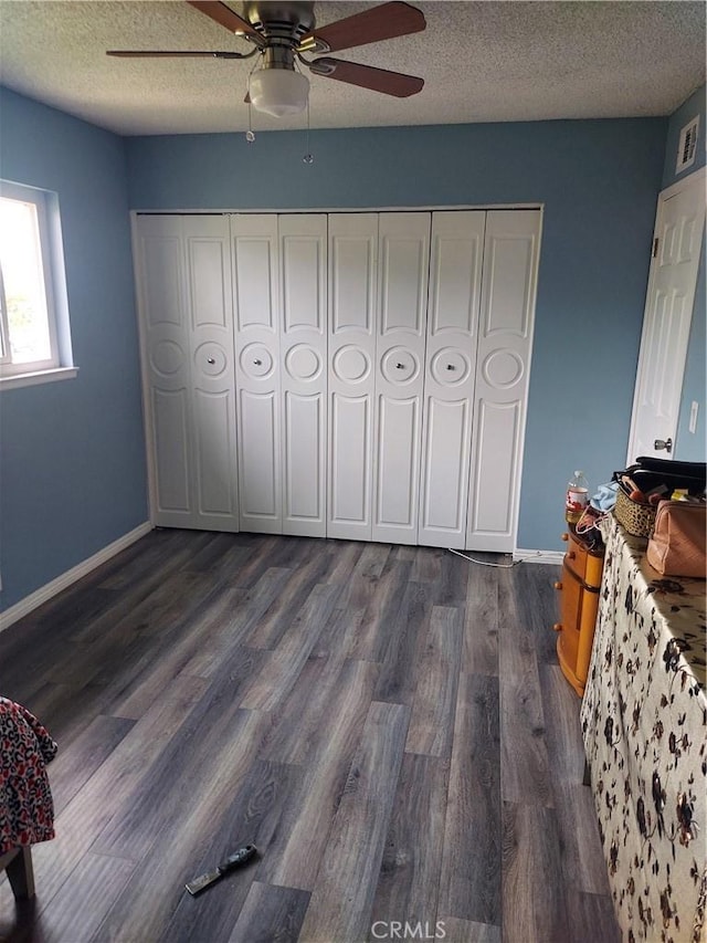 bedroom with dark wood-style floors, visible vents, baseboards, a textured ceiling, and ceiling fan