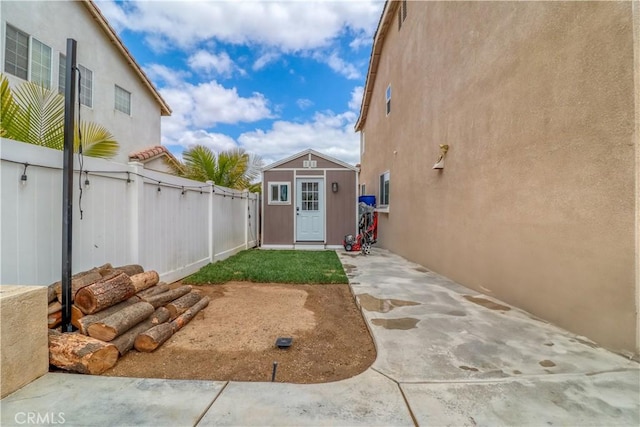 view of yard featuring an outbuilding, a fenced backyard, a patio area, and a storage unit