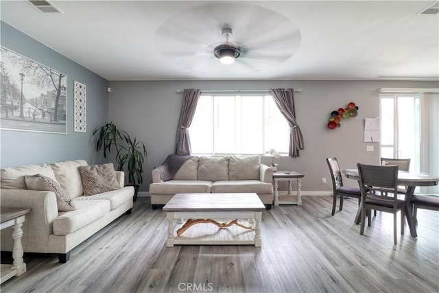 living room with a healthy amount of sunlight, ceiling fan, wood finished floors, and visible vents