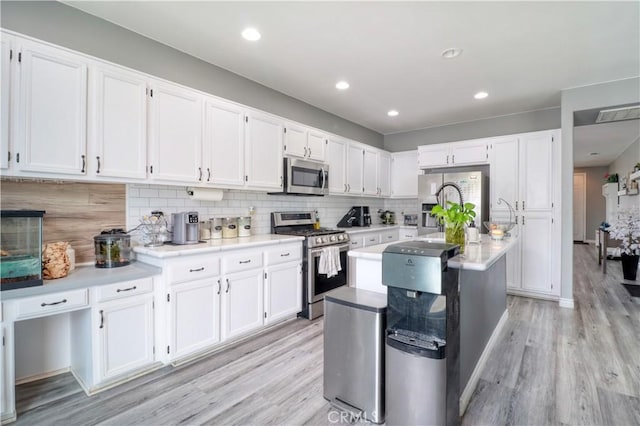kitchen featuring appliances with stainless steel finishes, white cabinets, and light wood-type flooring