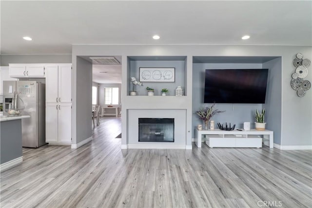 unfurnished living room with recessed lighting, baseboards, visible vents, and light wood finished floors