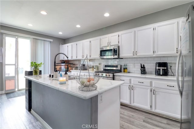 kitchen with plenty of natural light, stainless steel appliances, white cabinetry, and light wood-type flooring