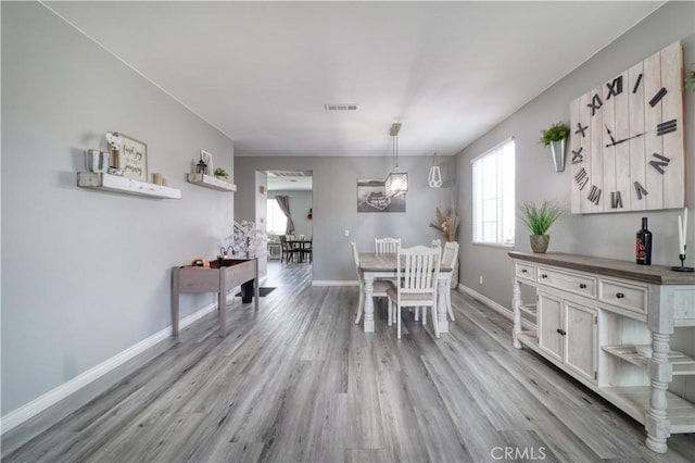 dining space featuring visible vents, light wood-style flooring, and baseboards