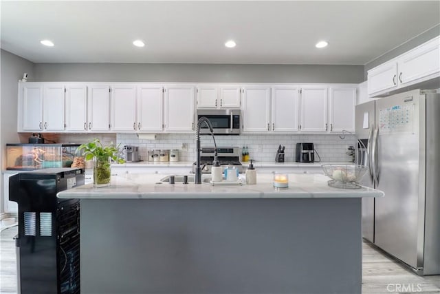 kitchen featuring appliances with stainless steel finishes, light wood finished floors, and white cabinetry