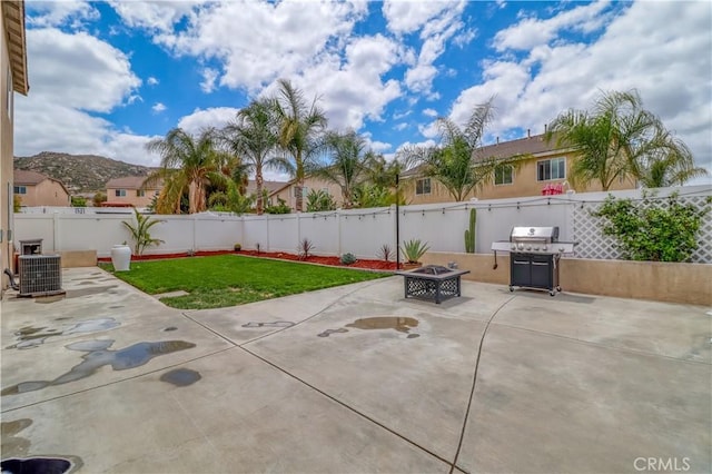 view of patio with a fenced backyard, an outdoor fire pit, central air condition unit, and grilling area