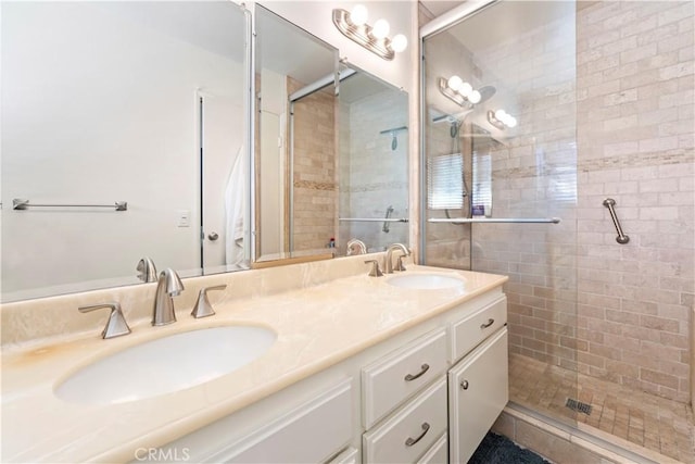 bathroom with a tile shower, double vanity, and a sink