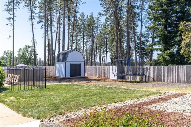 view of yard featuring a trampoline, an outdoor structure, a fenced backyard, and a storage shed