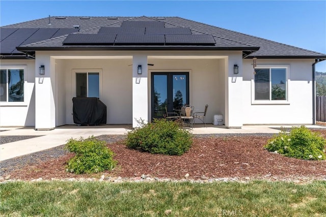 back of house featuring stucco siding, a patio area, and solar panels