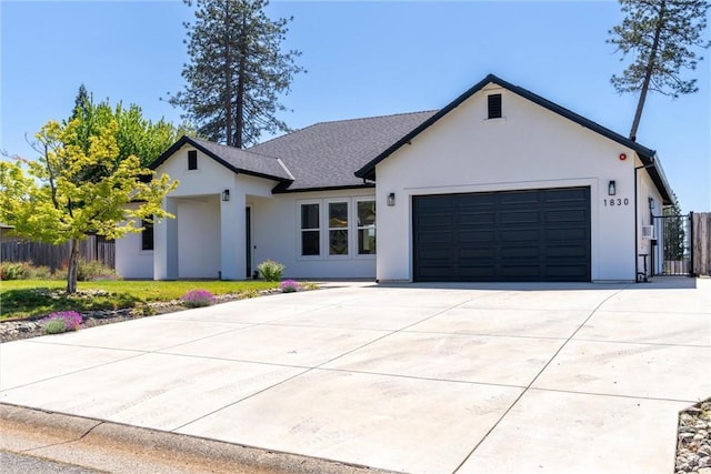 modern inspired farmhouse with a garage, driveway, roof with shingles, stucco siding, and fence