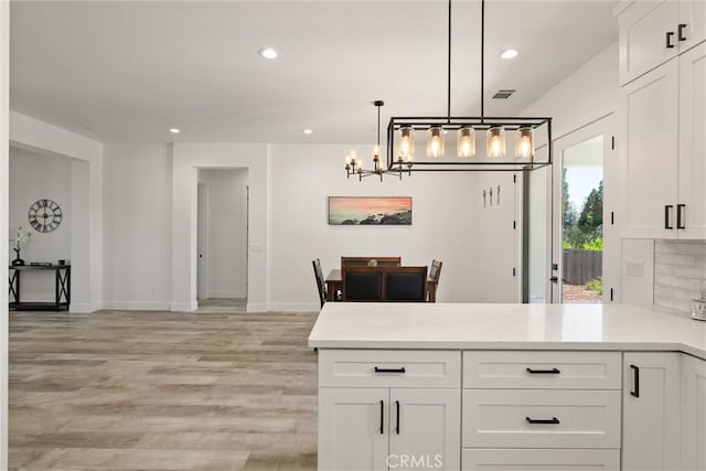 kitchen with white cabinetry, a peninsula, recessed lighting, and a chandelier