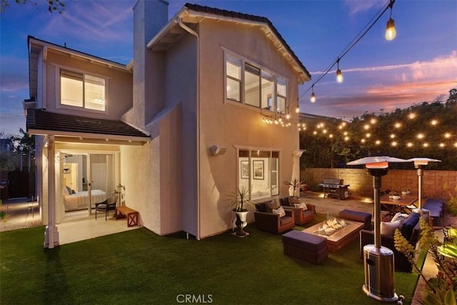 1711 Colina Terrestre, San Clemente, CA 92673 - back of property at dusk featuring an outdoor living space with a fire pit, a patio, a chimney, and stucco siding