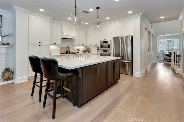 1711 Colina Terrestre, San Clemente, CA 92673 - kitchen with appliances with stainless steel finishes, custom range hood, light countertops, light wood finished floors, and a chandelier