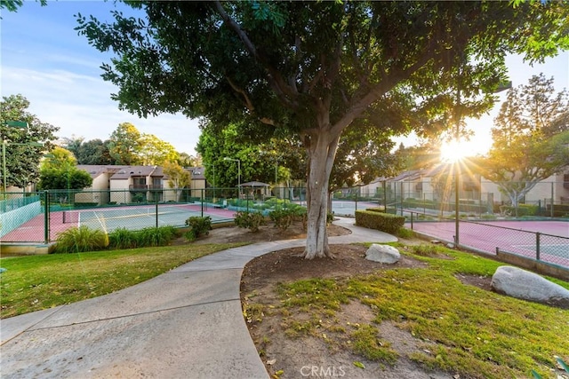 view of community with a tennis court, fence, and a residential view