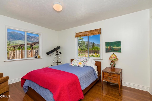 bedroom with wood finished floors, baseboards, and a mountain view