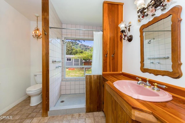 bathroom with vanity, a tile shower, and toilet