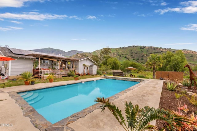 pool featuring an outbuilding, a deck with mountain view, and a shed
