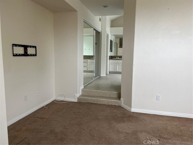 corridor featuring baseboards and carpet flooring