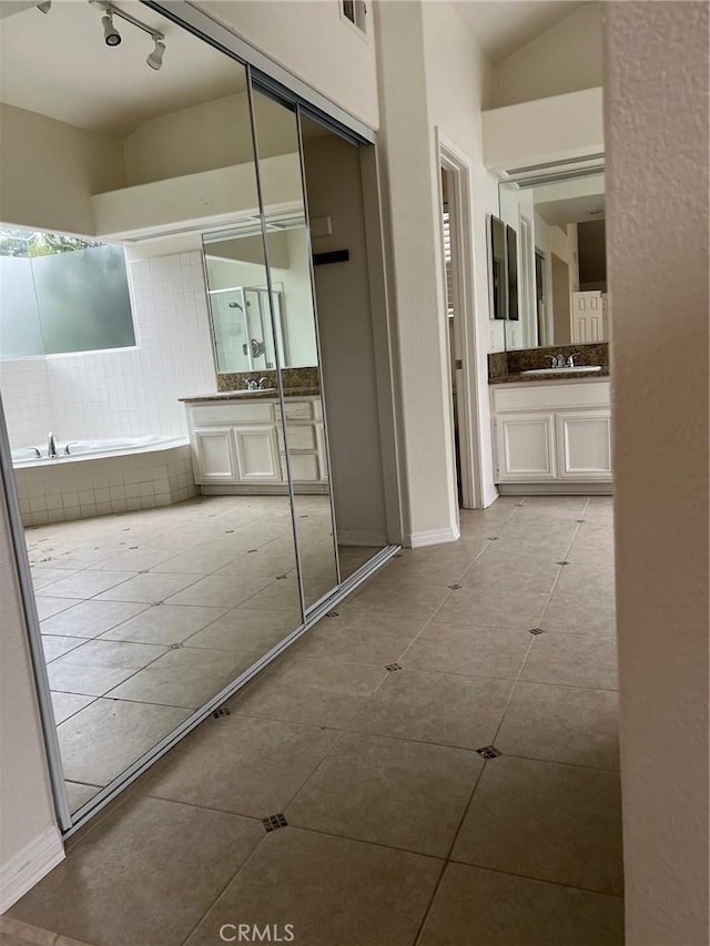 corridor with baseboards, a sink, tile patterned flooring, and rail lighting
