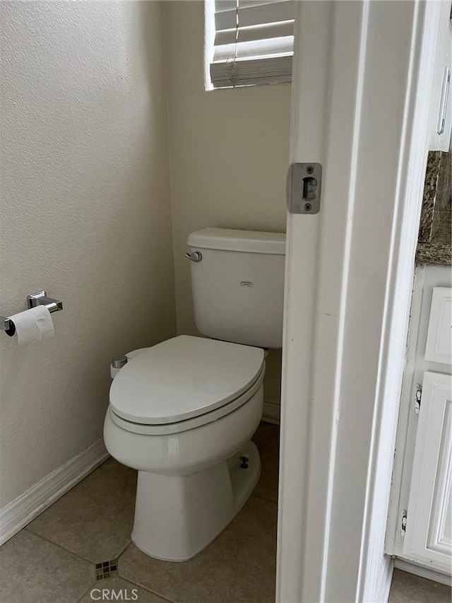 bathroom featuring baseboards, tile patterned flooring, and toilet