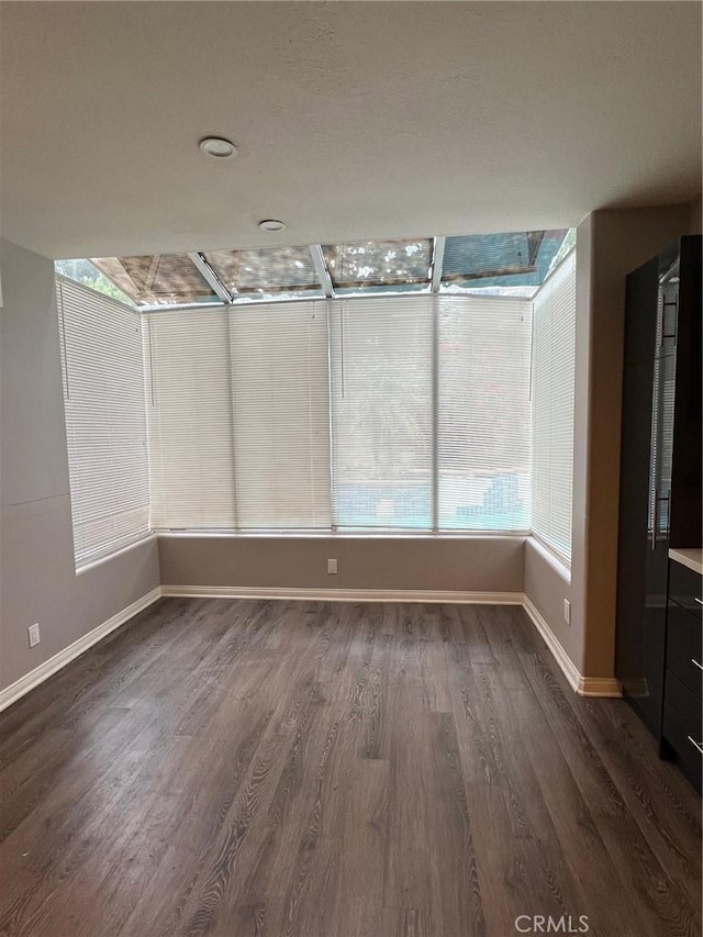 spare room featuring baseboards and dark wood-style flooring