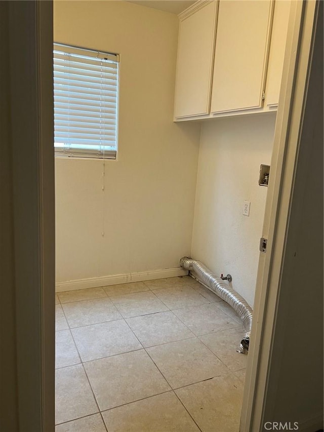 clothes washing area featuring cabinet space, baseboards, and light tile patterned floors