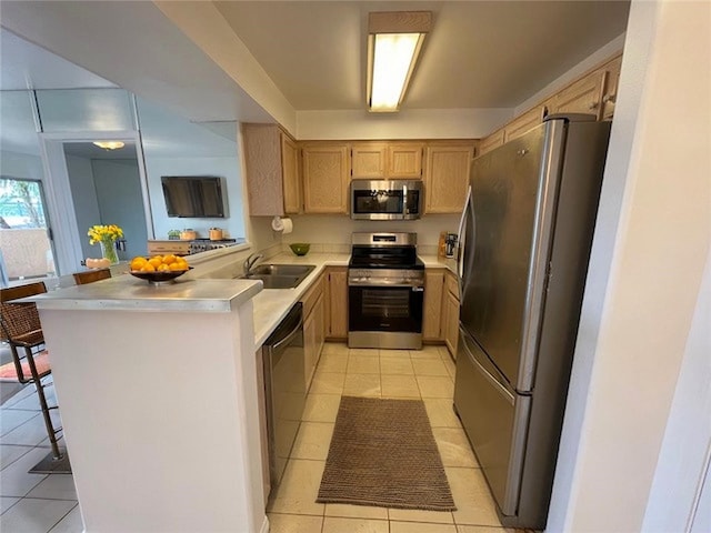 kitchen featuring a sink, stainless steel appliances, light tile patterned flooring, a peninsula, and light countertops