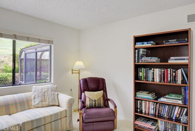 living area featuring baseboards, visible vents, and a textured ceiling