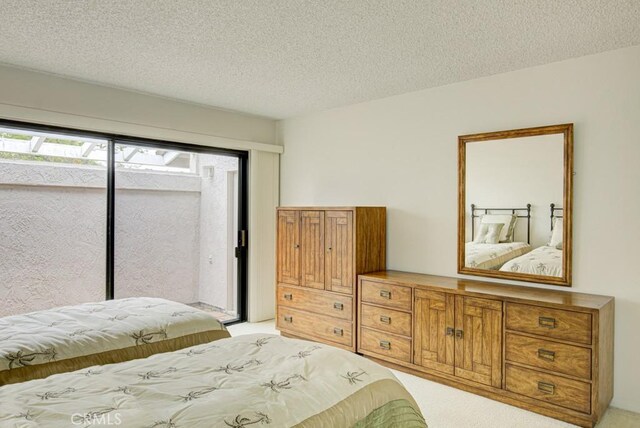 bedroom with access to exterior, light carpet, and a textured ceiling