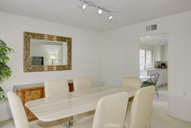 dining room with visible vents, rail lighting, and a textured ceiling