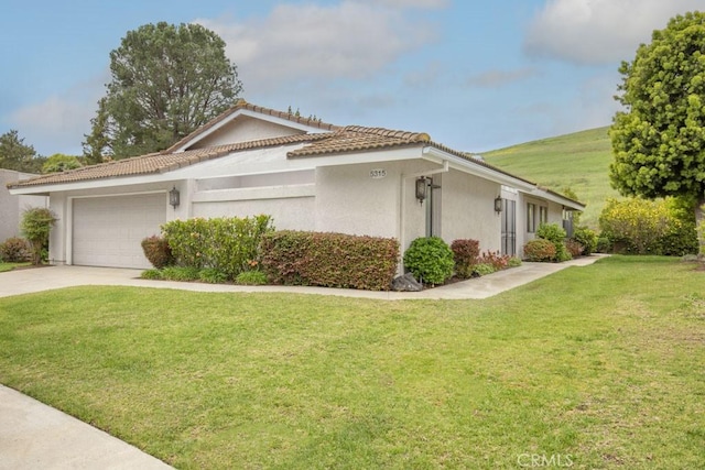 view of property exterior featuring driveway, a tiled roof, stucco siding, a yard, and a garage