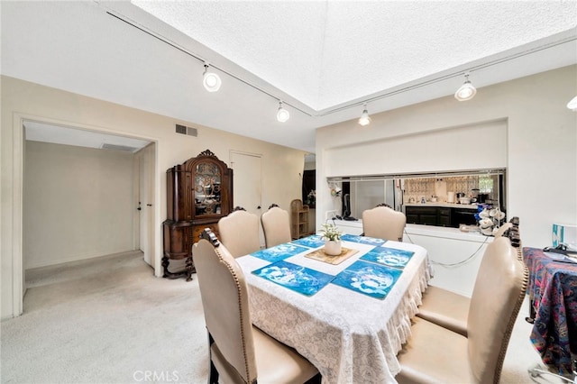 dining space with track lighting, visible vents, light colored carpet, and a textured ceiling