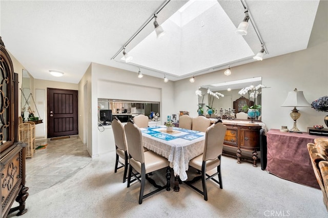 dining room with rail lighting, a textured ceiling, and light carpet