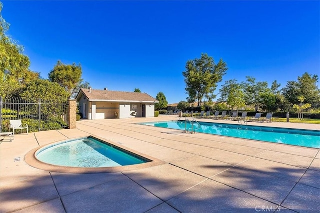 community pool featuring a hot tub, a patio area, and fence