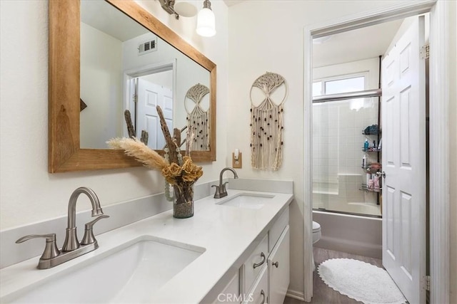bathroom with visible vents, a sink, double vanity, and toilet