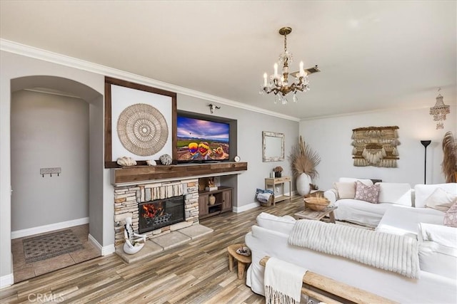 living room with arched walkways, wood finished floors, baseboards, a notable chandelier, and ornamental molding