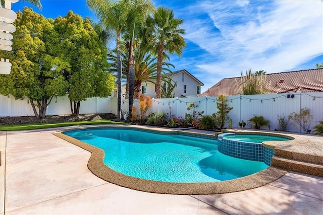 view of pool featuring a fenced backyard, a pool with connected hot tub, and a patio area