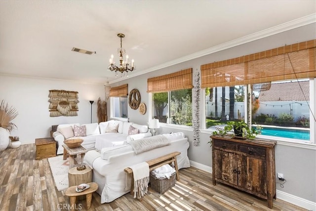 bedroom featuring an inviting chandelier, crown molding, visible vents, wood finished floors, and baseboards