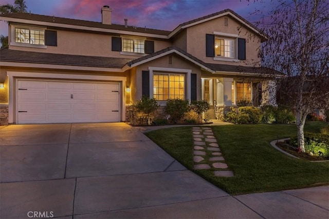 traditional-style home with driveway, a chimney, a lawn, a garage, and stucco siding