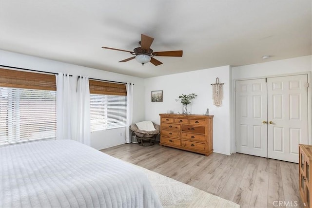bedroom with a ceiling fan, baseboards, a closet, and light wood-style floors