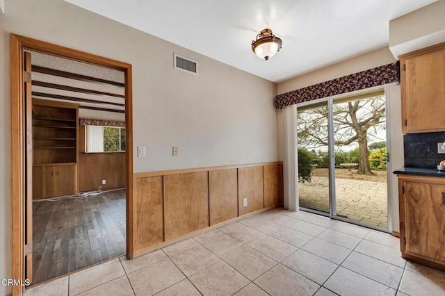 1530 Calle Portada, Camarillo, CA 93010 - unfurnished dining area with wood walls, wainscoting, visible vents, and light tile patterned floors