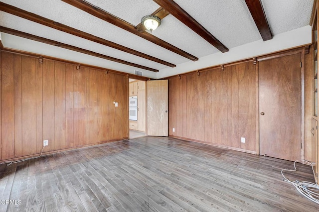 1530 Calle Portada, Camarillo, CA 93010 - empty room with beamed ceiling, wooden walls, wood finished floors, and a textured ceiling
