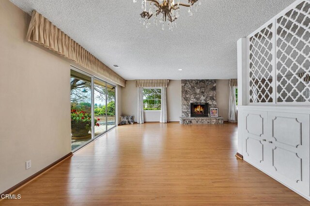 1530 Calle Portada, Camarillo, CA 93010 - unfurnished living room featuring a chandelier, a stone fireplace, a textured ceiling, and light wood-style floors