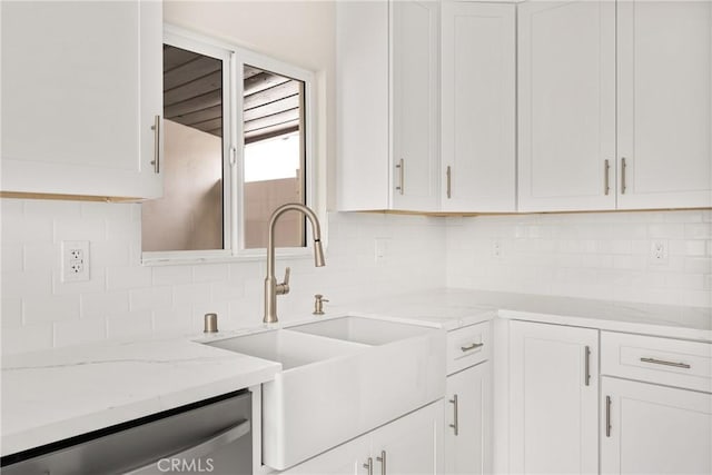 kitchen featuring light stone counters, backsplash, dishwasher, a sink, and white cabinetry