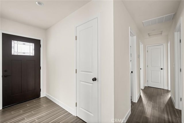 foyer entrance with baseboards, wood finished floors, and visible vents