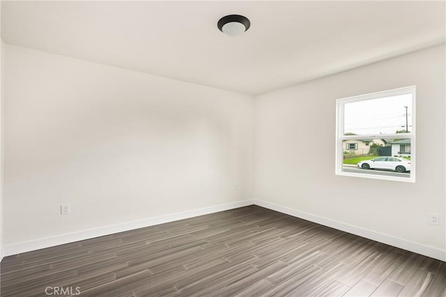 spare room featuring dark wood-type flooring and baseboards
